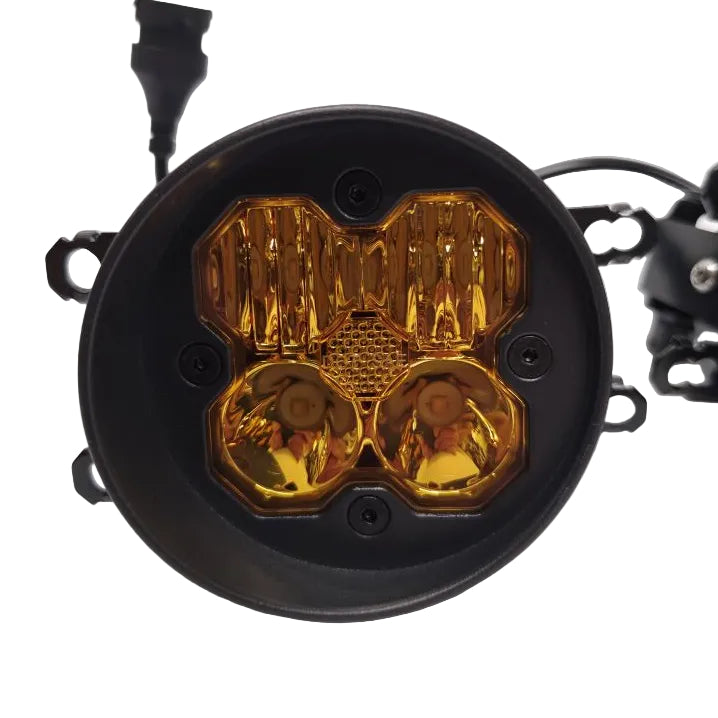 A round black automotive light fixture with a translucent amber/yellow lens and visible mounting hardware, photographed on a white studio background.